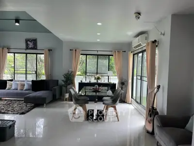 Spacious living room with modern decor and large windows offering lush garden views.