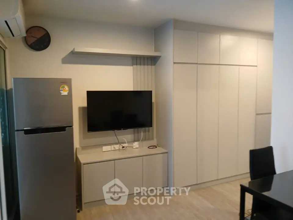 Modern living room with sleek cabinetry and wall-mounted TV in a stylish apartment.