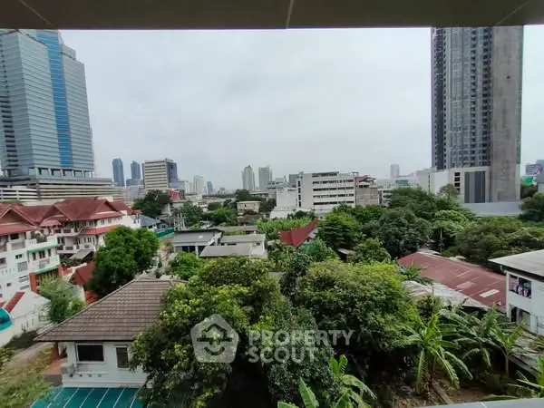 Stunning cityscape view from a high-rise balcony showcasing urban skyline and lush greenery.