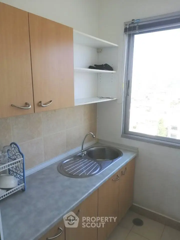Compact kitchen with window view and wooden cabinets, ideal for efficient cooking space.