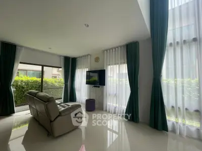 Spacious living room with modern recliner and large windows offering natural light