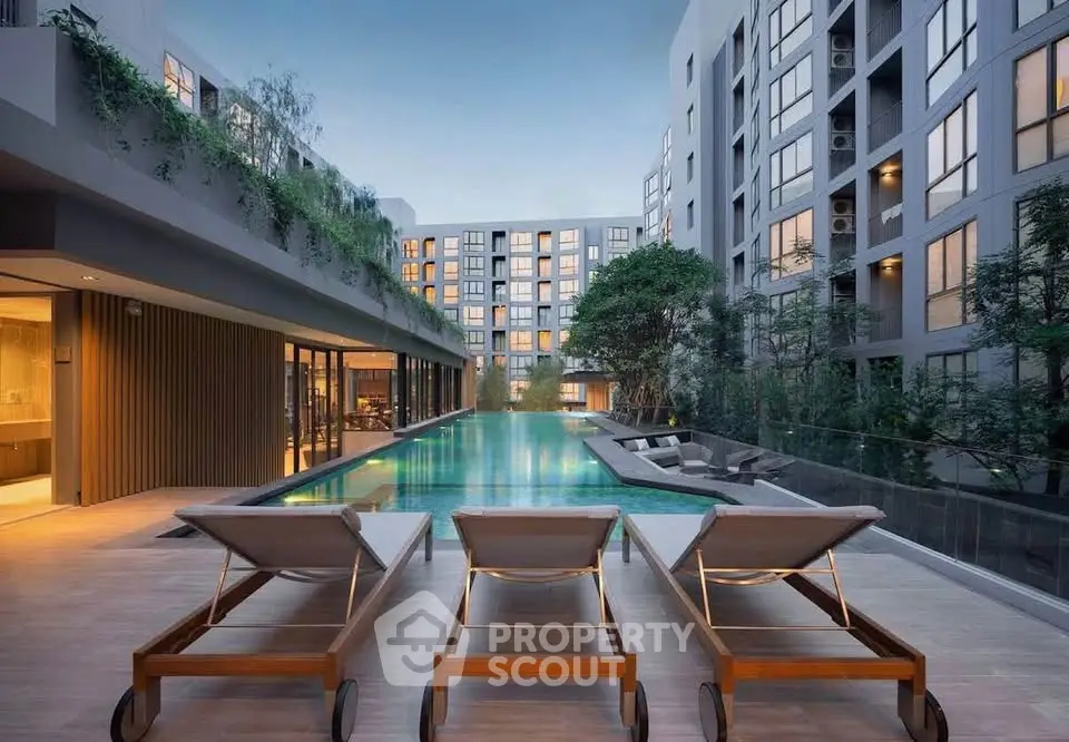 Luxurious modern apartment complex with stunning pool and elegant outdoor seating area.