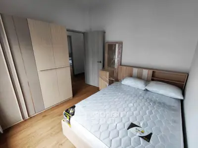 Modern bedroom with wooden flooring, stylish wardrobe, and comfortable bed in a contemporary apartment.