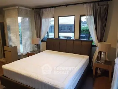 Spacious bedroom with large windows and elegant decor in a modern home.