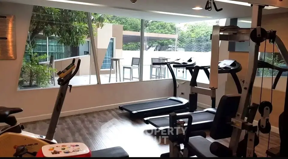 Modern gym with large windows and exercise equipment in a residential building.