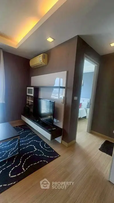 Modern living room with stylish decor and natural light, featuring a cozy TV area and adjacent bedroom.