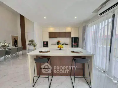 Modern kitchen with island and dining area, featuring sleek design and ample natural light.