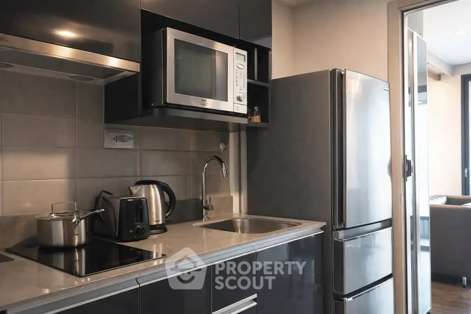 Modern kitchen with sleek appliances and open layout, featuring stainless steel fridge and microwave.