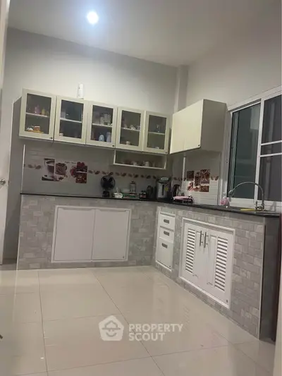 Modern kitchen with sleek cabinetry and tiled backsplash, featuring ample storage and counter space.