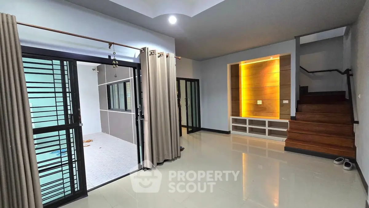 Spacious modern living area with sleek staircase and large windows for natural light.