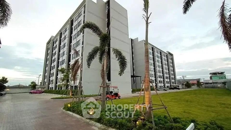 Modern apartment complex with lush landscaping and spacious parking area.