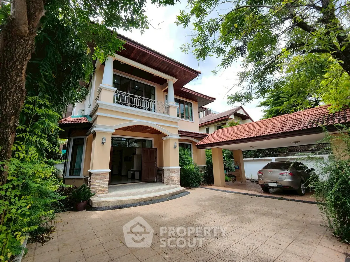 Elegant two-story house with carport and lush greenery, perfect for family living.
