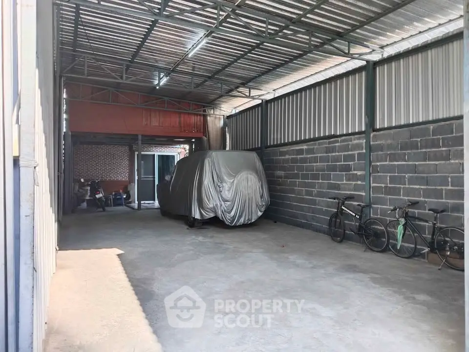 Spacious covered parking area with bicycles and a covered vehicle, ideal for secure storage.