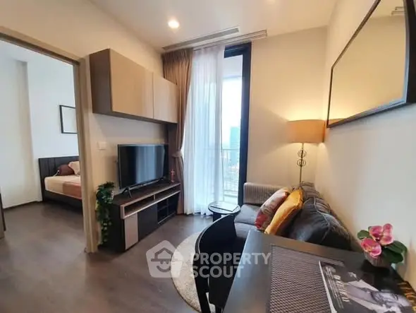 Modern living room with cozy seating and stylish decor, adjacent to a bedroom with natural light.