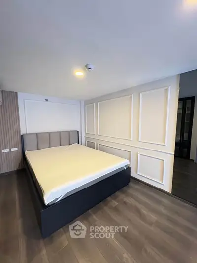 Spacious modern bedroom with elegant paneling and sleek flooring