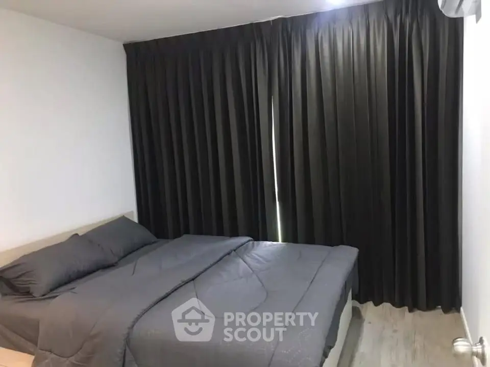 Cozy bedroom with dark curtains and modern bedding in a stylish apartment.