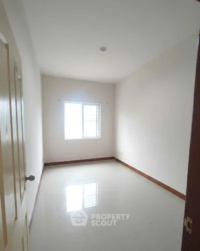 Spacious empty bedroom with large window and glossy floor, perfect for customization.