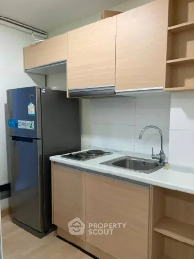 Modern compact kitchen with sleek cabinetry and stainless steel fridge