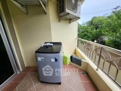 Charming balcony with washing machine and lush green view, perfect for convenient laundry and relaxation.