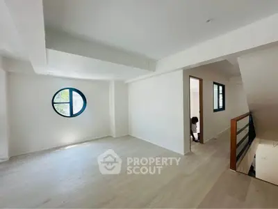 Spacious modern living room with unique round window and wooden flooring