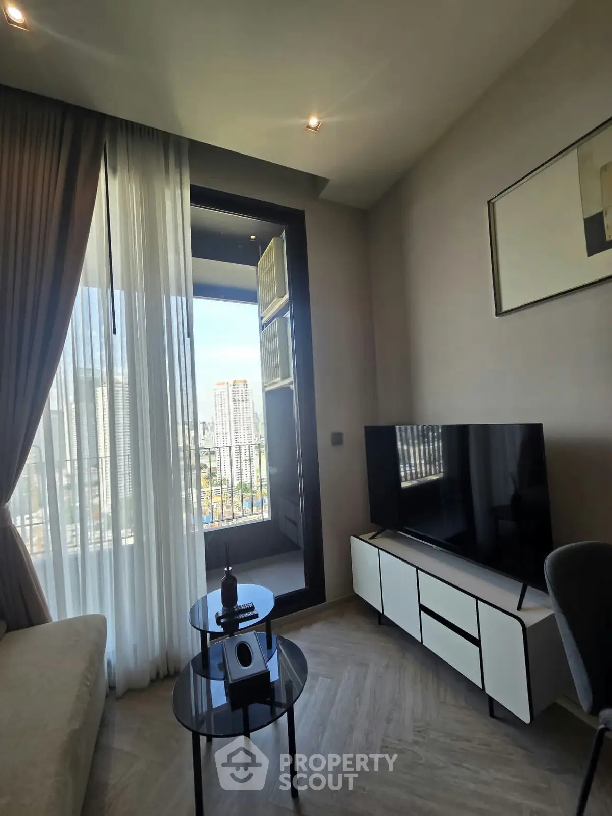 Modern living room with sleek TV setup and city view from balcony.