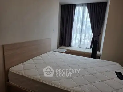 Cozy bedroom with large window and natural light, featuring a comfortable mattress and stylish decor.