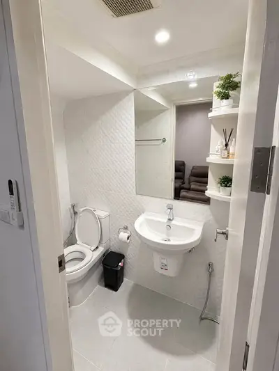 Modern bathroom with sleek fixtures and minimalist design, featuring a wall-mounted sink and toilet.