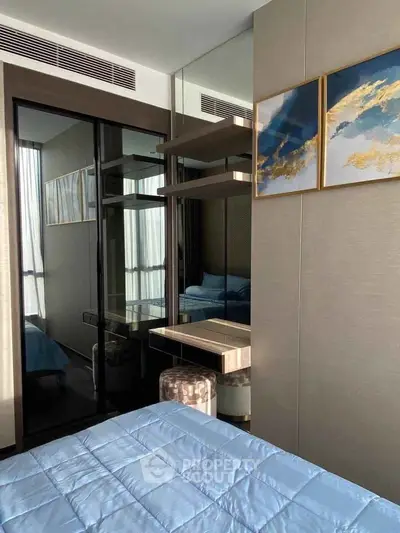 Modern bedroom with stylish decor and mirrored accents, featuring a cozy bed and elegant artwork.