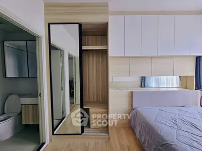 Modern bedroom with built-in wardrobe and ensuite bathroom in stylish apartment.