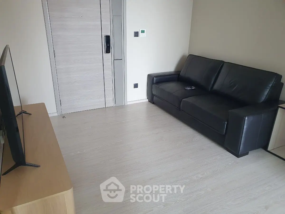 Modern living room with sleek black leather sofa and flat-screen TV.