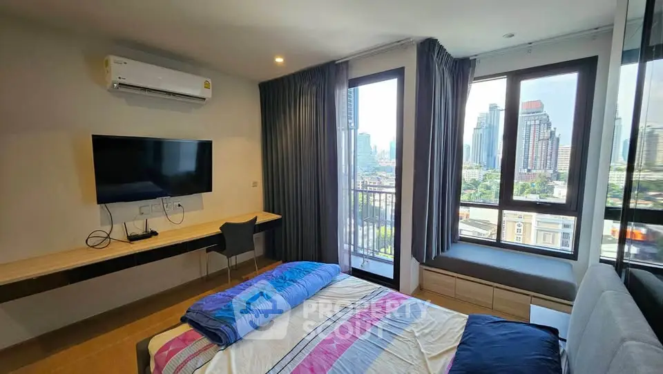 Modern bedroom with city view, featuring large windows and sleek furnishings.
