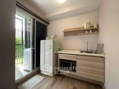 Compact kitchen with modern appliances and balcony access in urban apartment
