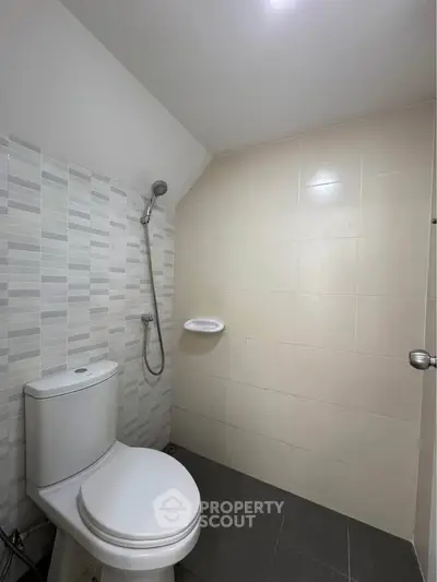 Modern minimalist bathroom with sleek tiles and shower area.