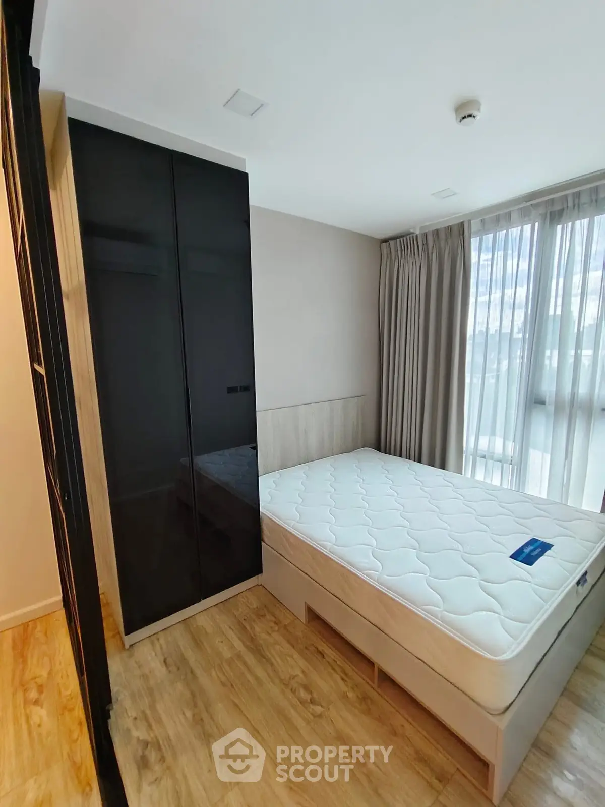 Modern bedroom with sleek black wardrobe and large window for natural light.