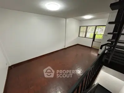 Spacious living room with wooden flooring and natural light from large window.