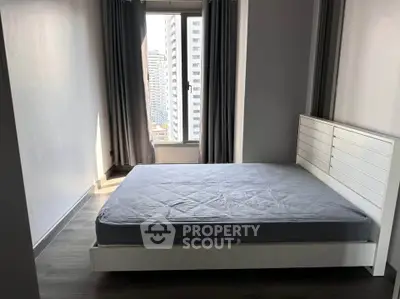 Modern bedroom with large window and city view, featuring a sleek bed and minimalist decor.