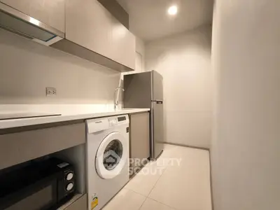 Modern kitchen with washing machine and fridge in sleek apartment