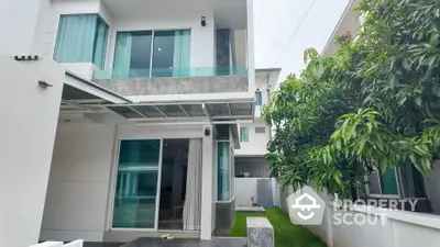 Modern two-story house with large windows and lush garden, offering a serene and stylish living environment.