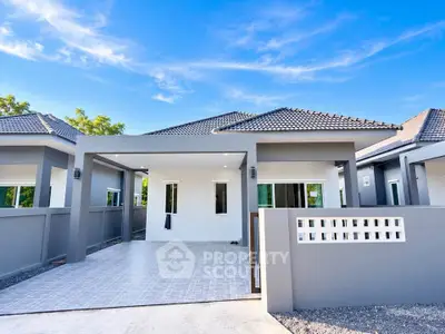 Modern single-story house with sleek design and spacious driveway under a clear blue sky.