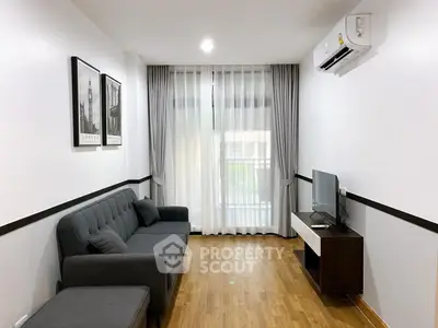 Modern living room with sleek design, featuring a comfortable sofa, wall art, and a flat-screen TV.