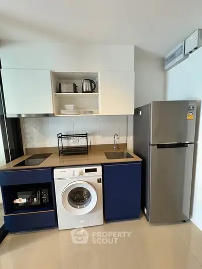 Modern kitchen with sleek appliances including washing machine and fridge, ideal for urban living.