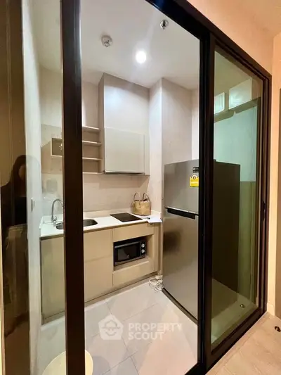 Modern compact kitchen with sleek appliances and stylish cabinetry in a cozy apartment.