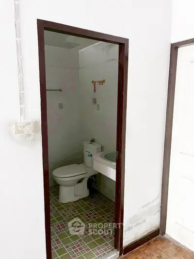 Compact bathroom with tiled floor and basic fixtures in a residential property.