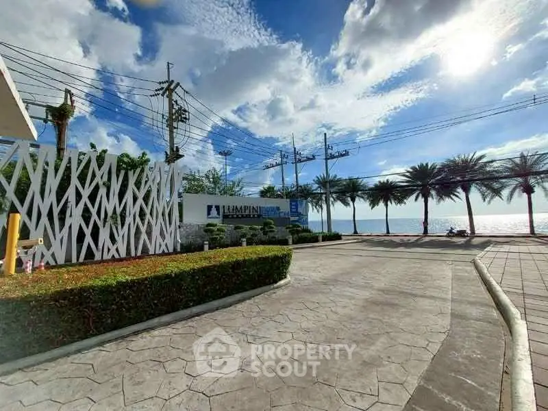 Stunning beachfront property entrance with palm trees and ocean view.