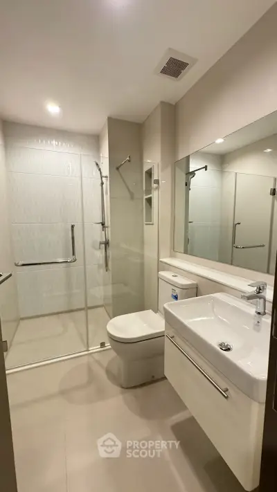 Modern bathroom with glass shower and sleek fixtures in a contemporary apartment.