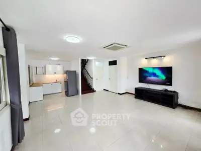 Spacious modern living room with sleek design and large TV, perfect for entertainment.