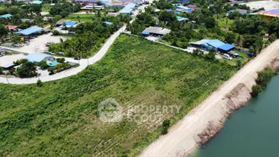 Scenic aerial view of lush green land by a serene river, ideal for development opportunities.