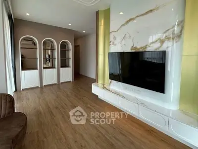 Modern living room with elegant built-in shelves and large TV on marble accent wall.