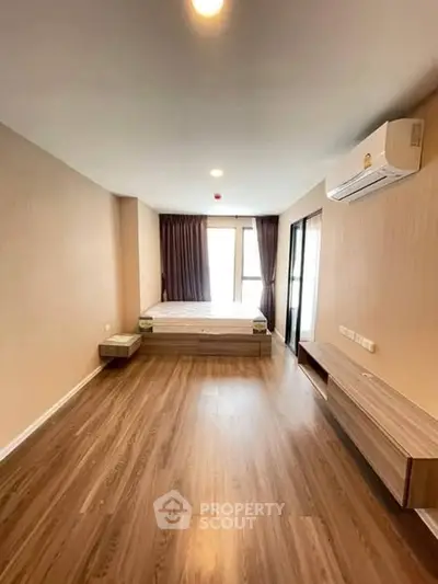 Spacious modern bedroom with wooden flooring and natural light