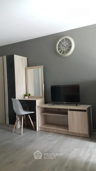 Modern living room with stylish furniture and wall clock, featuring a sleek TV stand and chair.